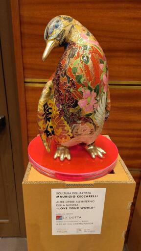 Una bellissima statua di un meraviglioso pinguino. Autore Maurizio Ceccarelli. Il pinguino con becco d'orato mostra un'ala con fiori gialli e d'oro.
