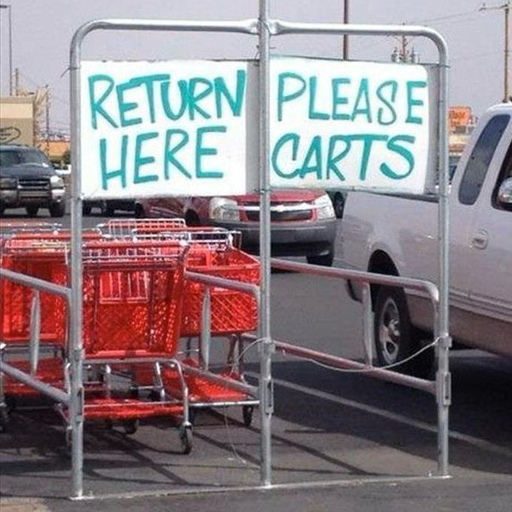 A sign structure instructs customers to return shopping carts in a designated area, featuring the text "RETURN HERE, PLEASE CARTS." Several red shopping carts are visible in the designated return space within a parking lot.
